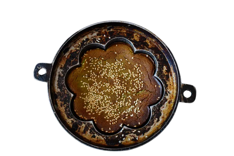 Traditional brass mould with freshly baked kuih bakar topped with sesame seeds